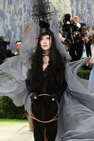 Madonna wears a brunette wig top hat and towering veil headpiece.